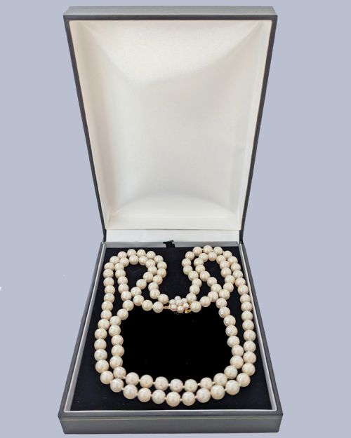 fig 6. A double-strand cultured pearl necklace featuring uniform cream pearls fastened with a floral cluster gold clasp.