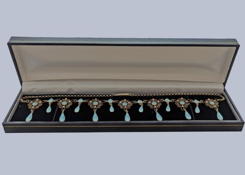 fig 6. An Art Nouveau silver gilt festoon necklace featuring filigree scrollwork, turquoise guilloche enamel discs, and suspended teardrop pendants.