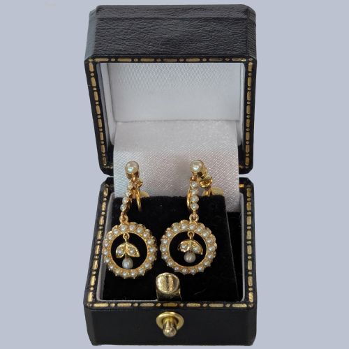 fig 4. A pair of Edwardian 15ct yellow gold drop earrings featuring circular seed pearl frames around foliate central motifs with screw-back fittings.