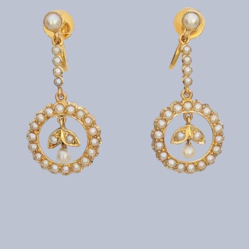 fig 5. A pair of Edwardian 15ct yellow gold drop earrings featuring circular seed pearl frames around foliate central motifs with screw-back fittings.