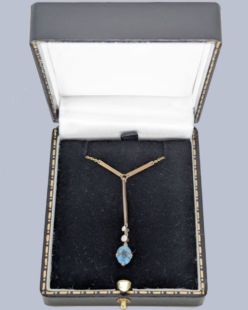 fig 5. An Edwardian 15ct yellow gold lavalier pendant necklace featuring a geometric bar drop, two millegrain-set old cut diamonds, and an oval blue topaz gemstone.