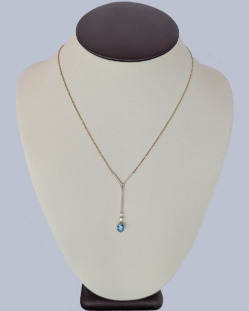 fig 6. An Edwardian 15ct yellow gold lavalier pendant necklace featuring a geometric bar drop, two millegrain-set old cut diamonds, and an oval blue topaz gemstone.
