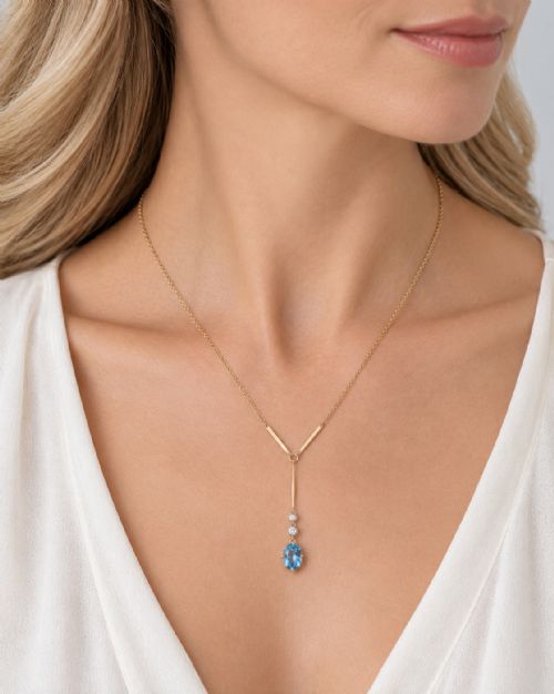 fig 7. An Edwardian 15ct yellow gold lavalier pendant necklace featuring a geometric bar drop, two millegrain-set old cut diamonds, and an oval blue topaz gemstone.