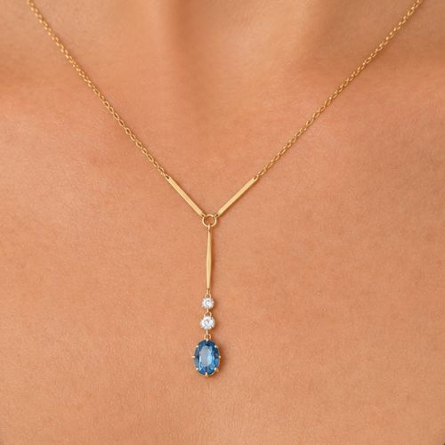 fig 8. An Edwardian 15ct yellow gold lavalier pendant necklace featuring a geometric bar drop, two millegrain-set old cut diamonds, and an oval blue topaz gemstone.