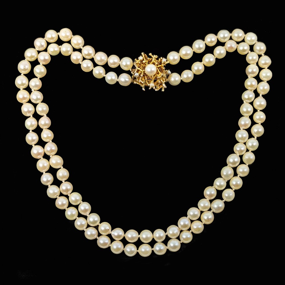 A double strand cream pearl necklace featuring an abstract textured gold centre clasp with a central pearl accent. View IV