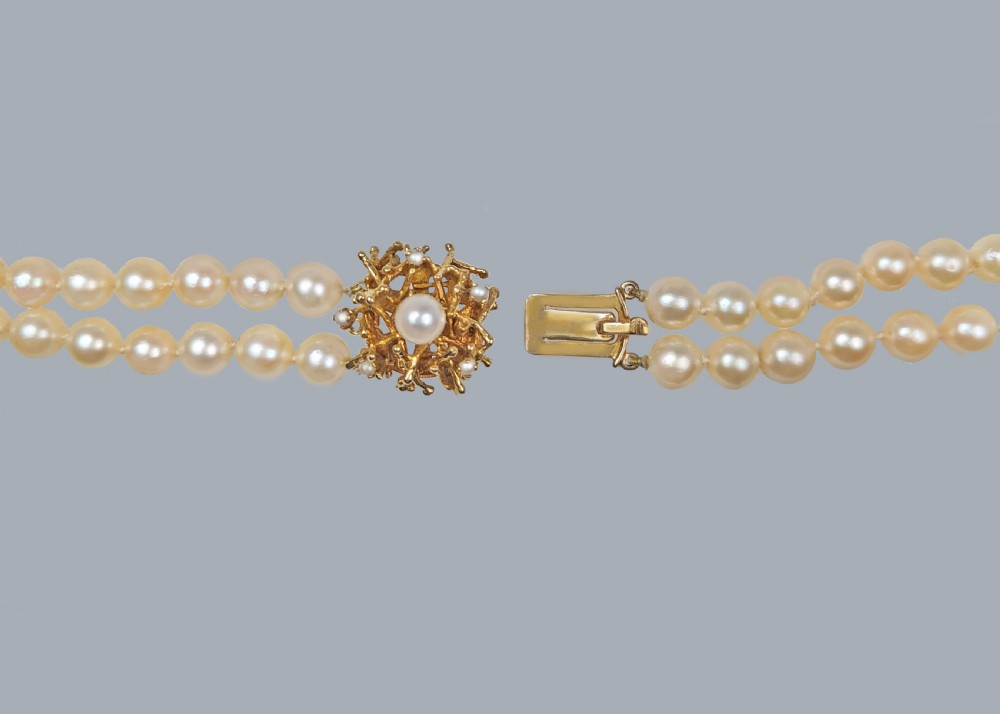 A double strand cream pearl necklace featuring an abstract textured gold centre clasp with a central pearl accent. View V
