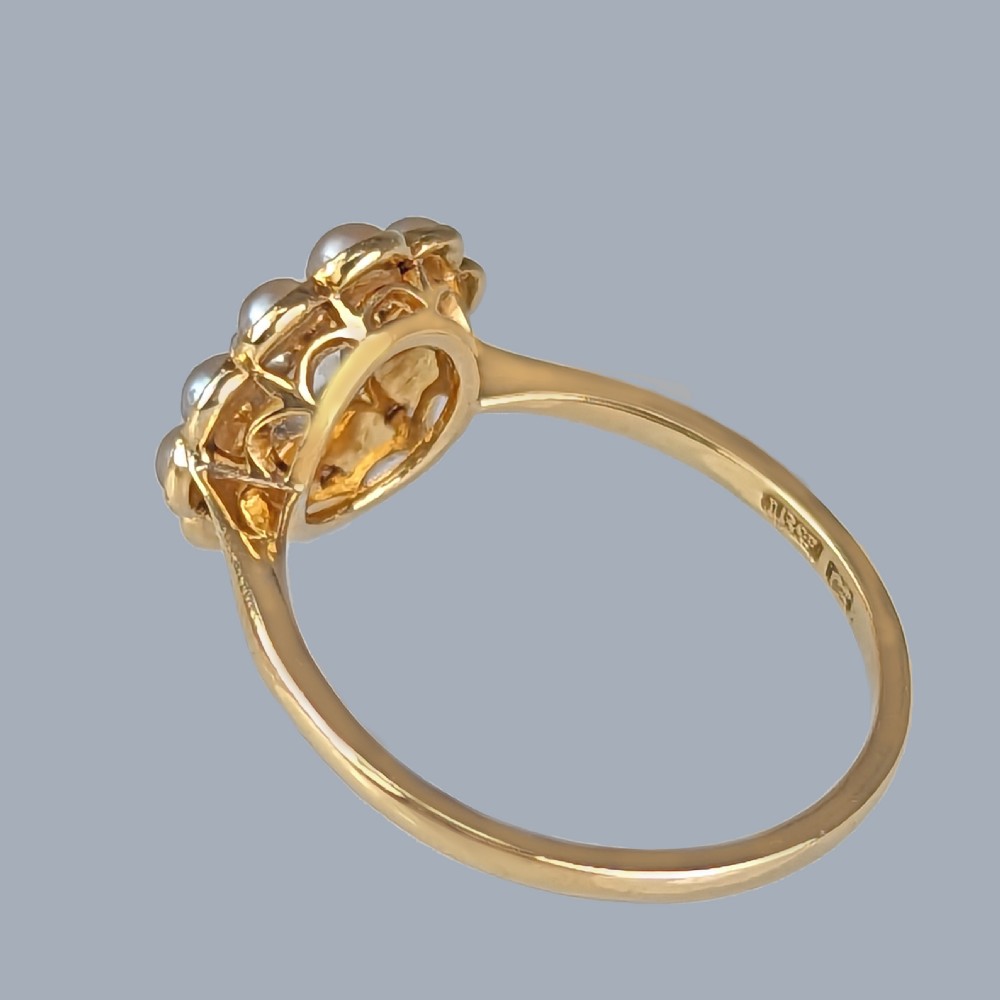 An Edwardian cluster ring featuring a central old-cut diamond surrounded by ten pearls set in 18ct yellow gold and platinum. View V