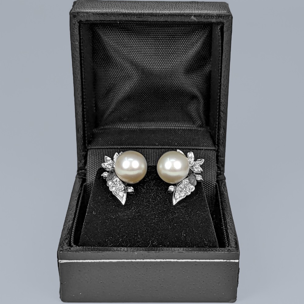 A pair of vintage 14ct white gold earrings featuring a central round pearl flanked by leaf-shaped clusters of small diamonds. View VIII
