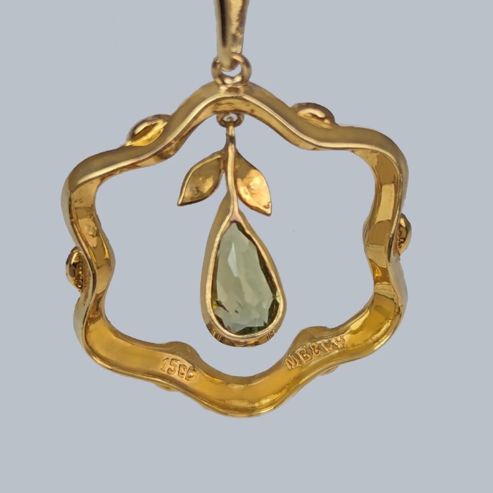 An Art Nouveau 15ct gold openwork pendant set with seed pearls around the rim and suspending a central pear-shaped peridot gemstone. View III