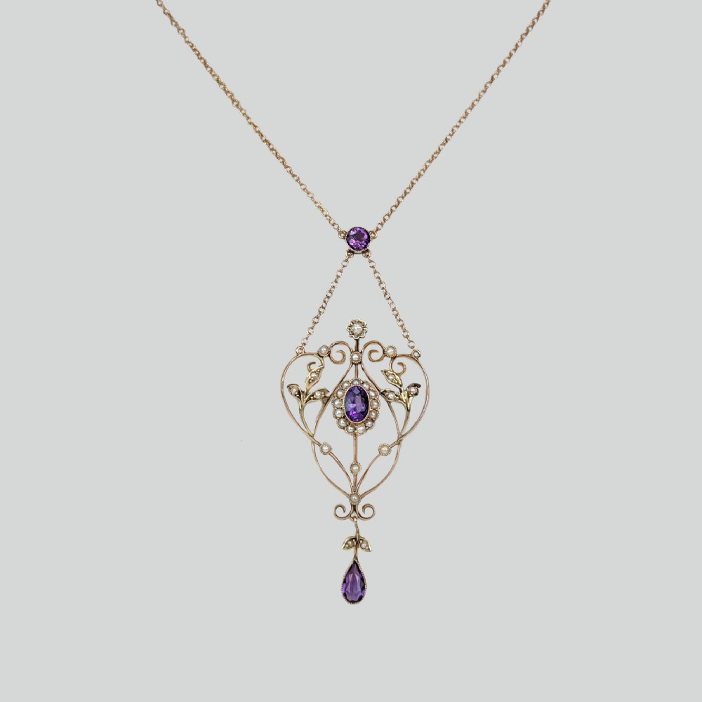 An Edwardian 9ct gold openwork lavalier pendant set with oval and pear-cut amethysts and seed pearls on a chain.