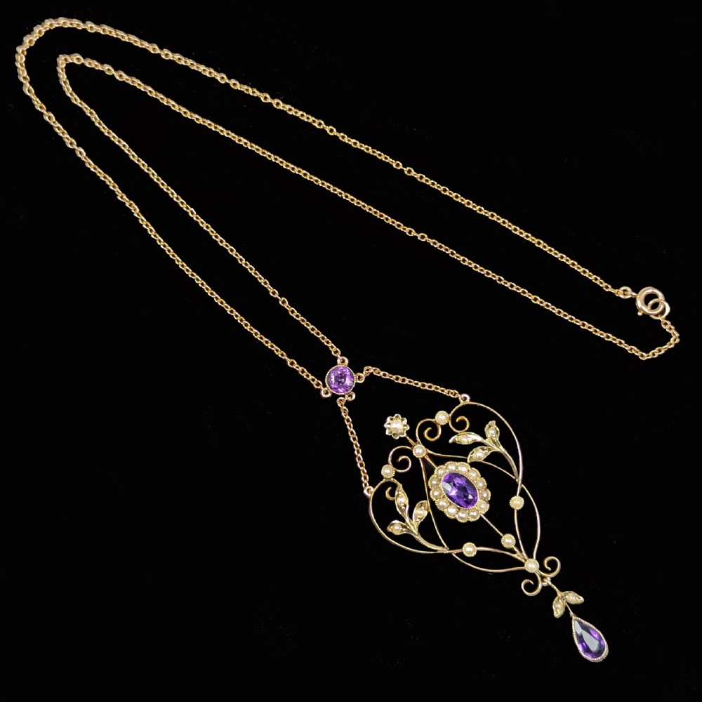 An Edwardian 9ct gold openwork lavalier pendant set with oval and pear-cut amethysts and seed pearls on a chain. View II