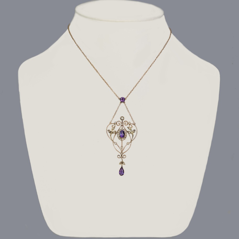 An Edwardian 9ct gold openwork lavalier pendant set with oval and pear-cut amethysts and seed pearls on a chain. View IV