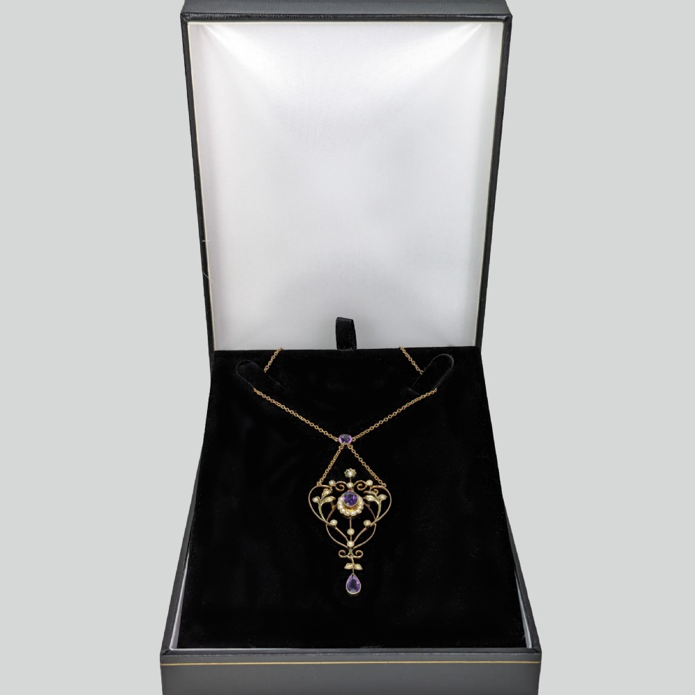 An Edwardian 9ct gold openwork lavalier pendant set with oval and pear-cut amethysts and seed pearls on a chain. View V