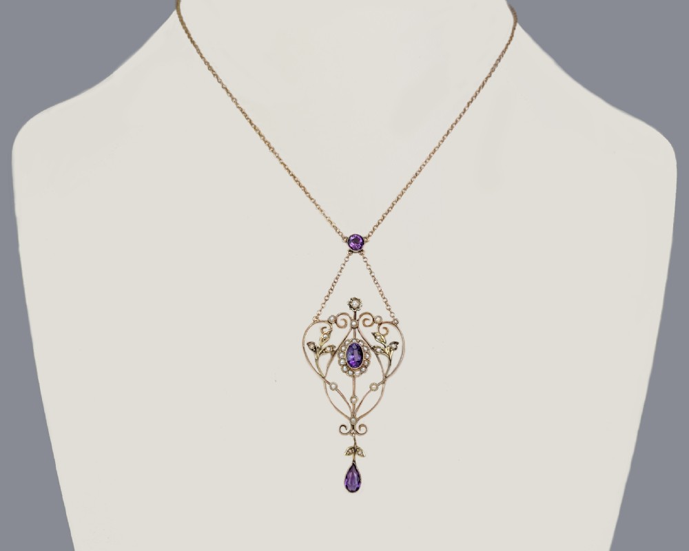 An Edwardian 9ct gold openwork lavalier pendant set with oval and pear-cut amethysts and seed pearls on a chain. View VI
