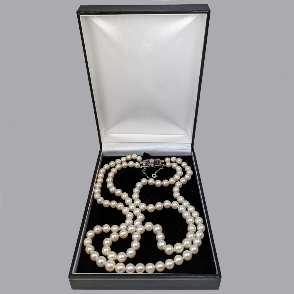 A double strand cream cultured pearl necklace featuring a rectangular 18ct gold clasp set with sapphires, rubies, and diamonds. View VII