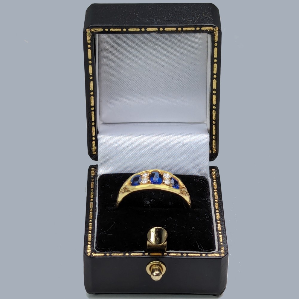 An antique Victorian 18ct yellow gold ring set with three blue sapphires and four old-cut diamonds in a boat-shaped setting with carved shoulders. View VI