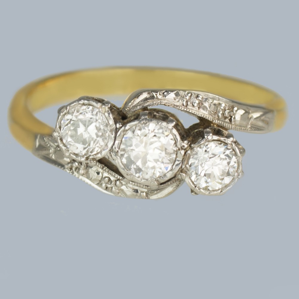 An Edwardian 18ct yellow gold trilogy ring with three round diamonds set diagonally in a platinum twist setting.