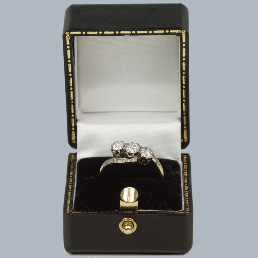 An Edwardian 18ct yellow gold trilogy ring with three round diamonds set diagonally in a platinum twist setting. View V