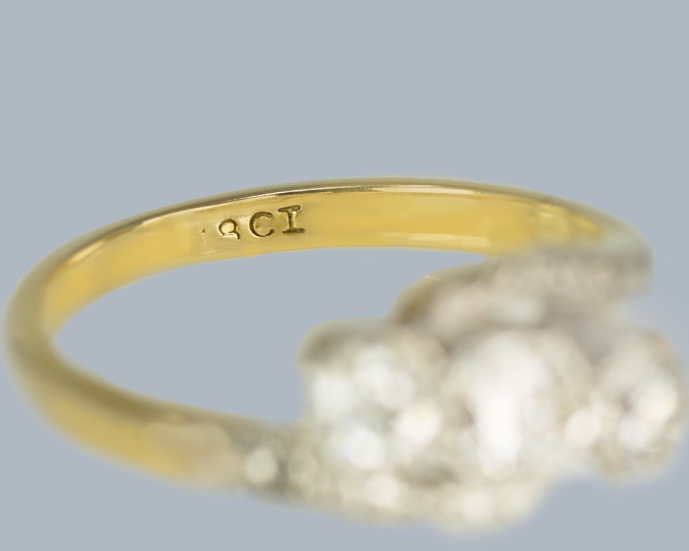 An Edwardian 18ct yellow gold trilogy ring with three round diamonds set diagonally in a platinum twist setting. View VI