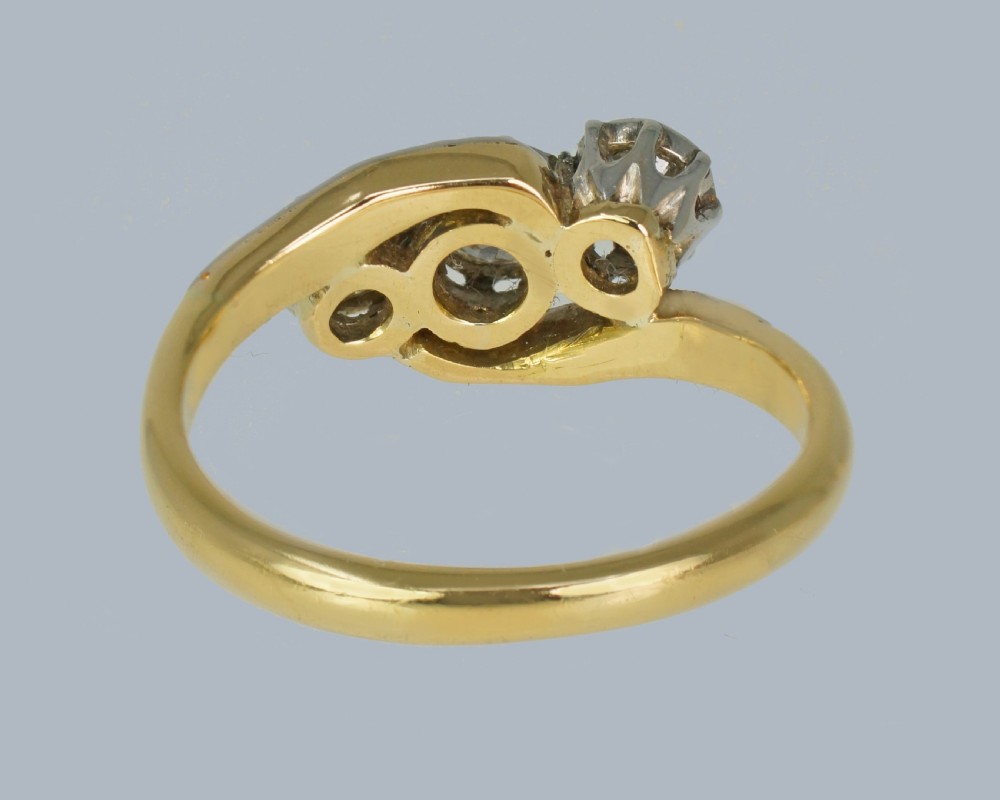 An Edwardian 18ct yellow gold trilogy ring with three round diamonds set diagonally in a platinum twist setting. View VII