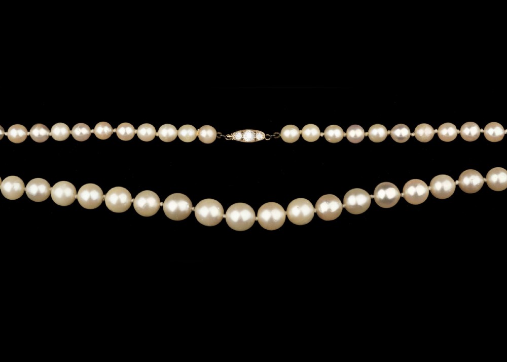 A single strand of cream-coloured pearls fitted with a central clasp set with three old cut diamonds. View II