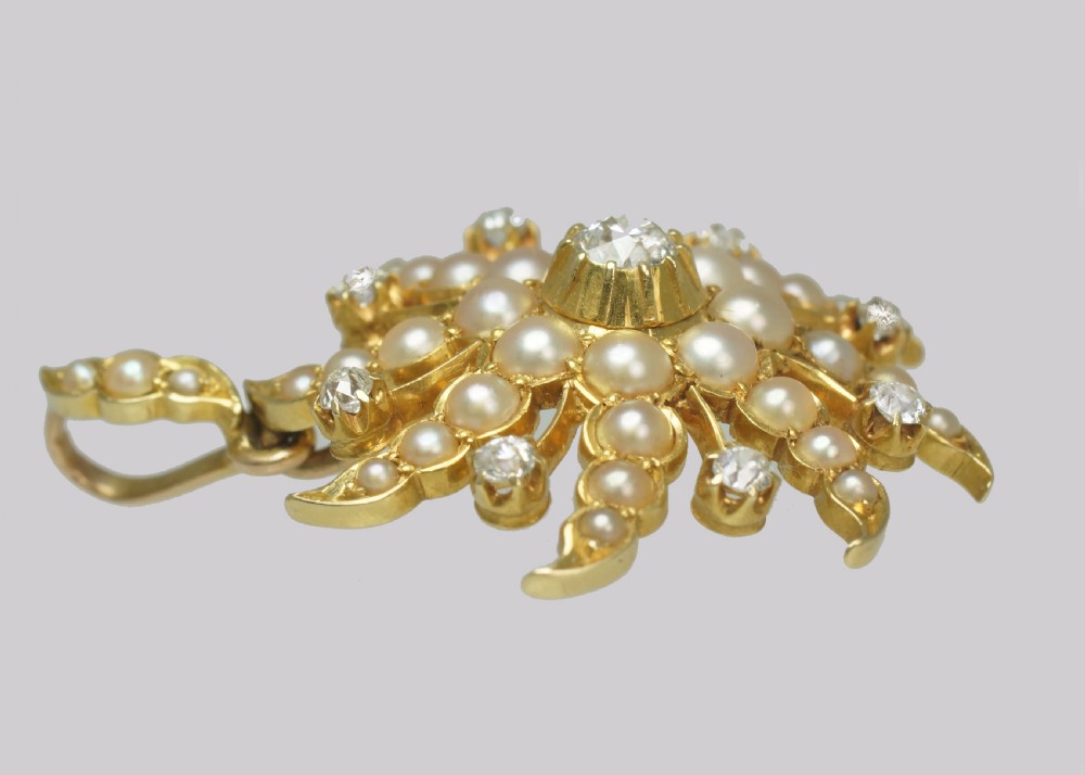 An 18ct yellow gold starburst pendant set with a central old cut diamond and accent diamonds, surrounded by graduated seed pearls along swirling rays. View V