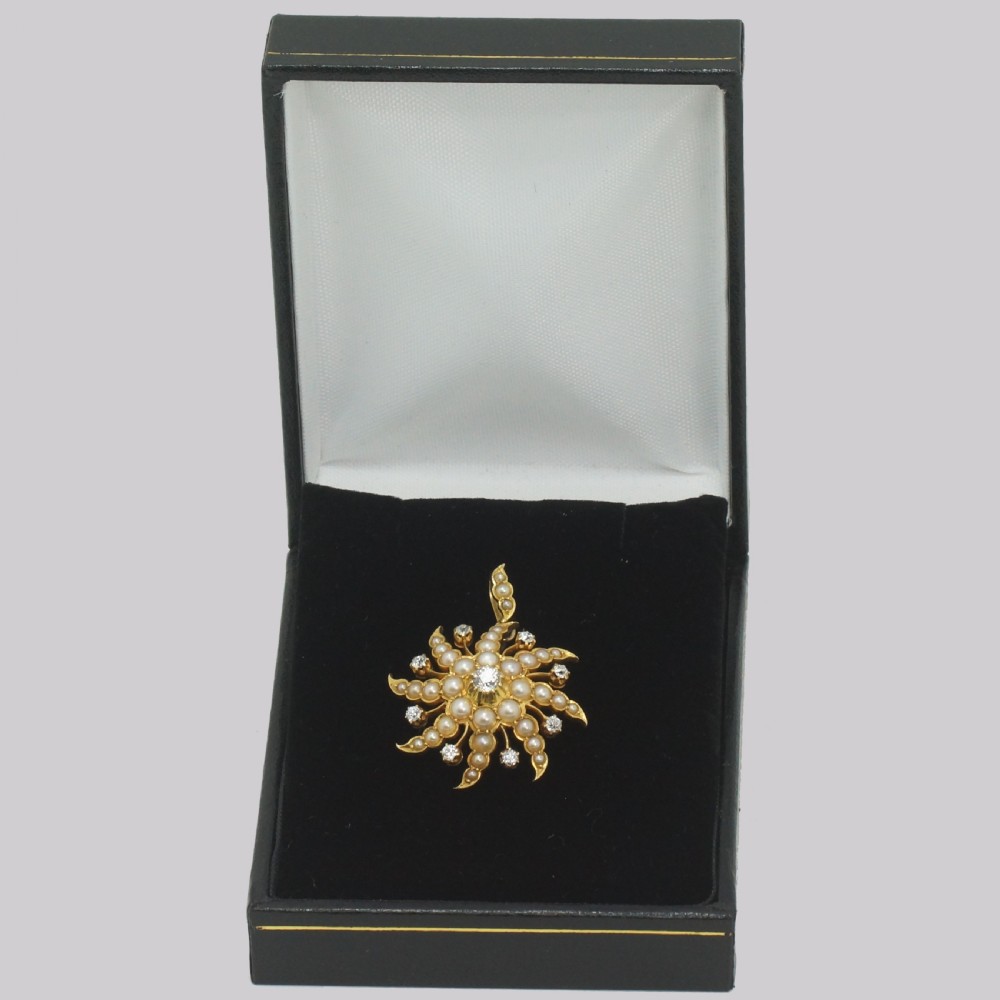 An 18ct yellow gold starburst pendant set with a central old cut diamond and accent diamonds, surrounded by graduated seed pearls along swirling rays. View VI