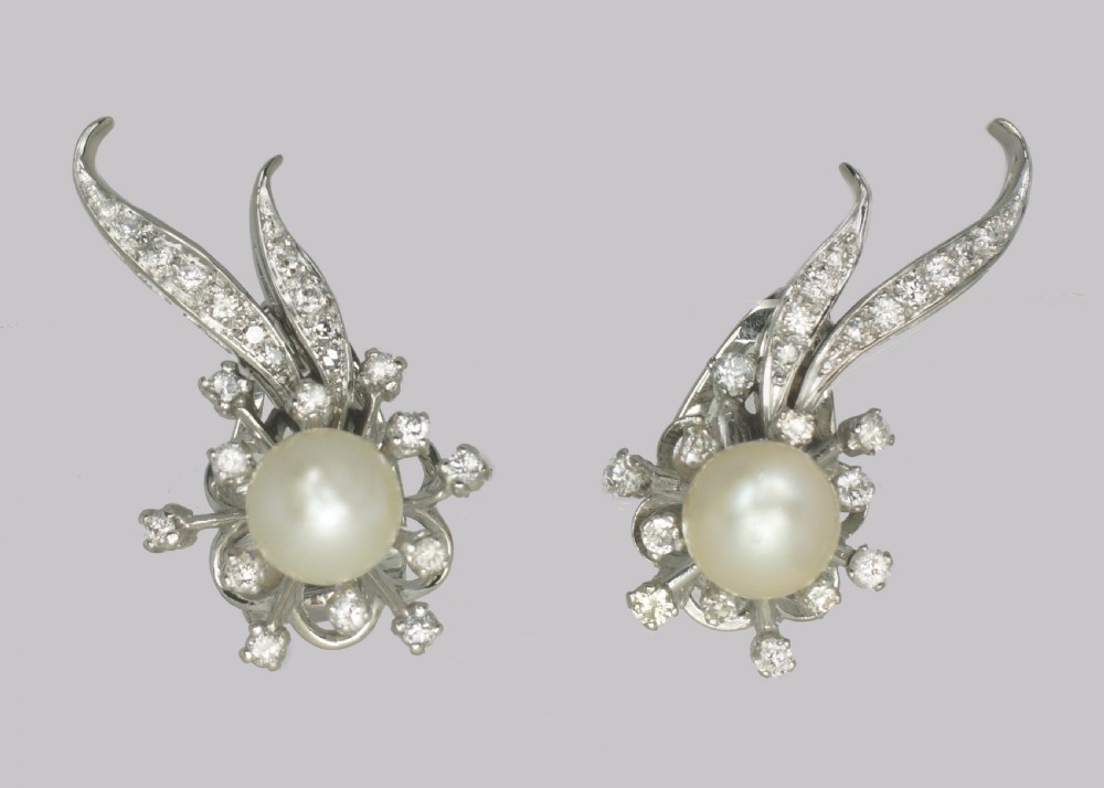 A pair of 1950s 18ct white gold clip-on earrings featuring central cultured pearls surrounded by diamond-set floral sprays and sweeping curved accents. View VIII