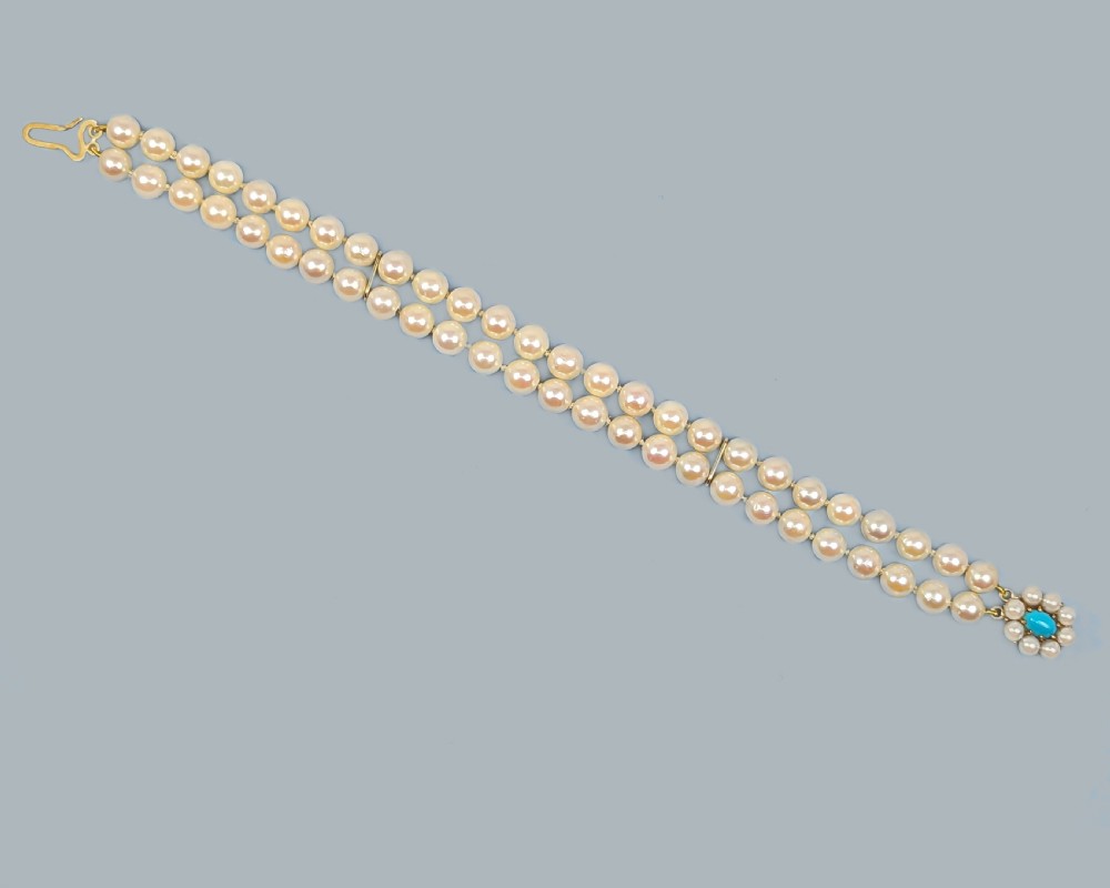A vintage double strand pearl bracelet featuring cream pearls connected by a 9ct yellow gold clasp with a central turquoise stone surrounded by seed pearls. View IV
