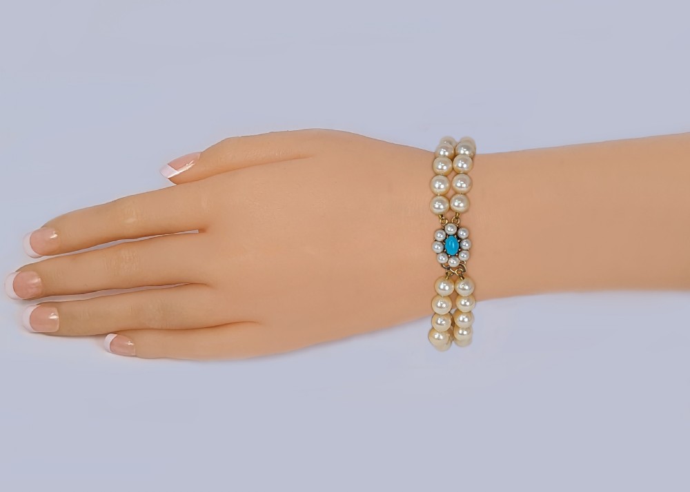 A vintage double strand pearl bracelet featuring cream pearls connected by a 9ct yellow gold clasp with a central turquoise stone surrounded by seed pearls. View VII