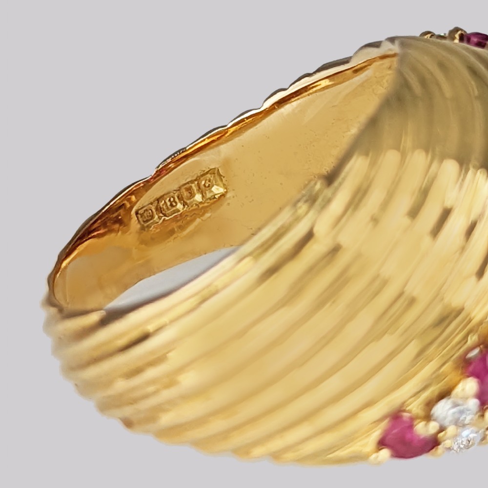 A mid-century 18ct yellow gold bombe ring styled with a ribbed textured surface and a diagonal band set with rubies and round brilliant diamonds. View VIII