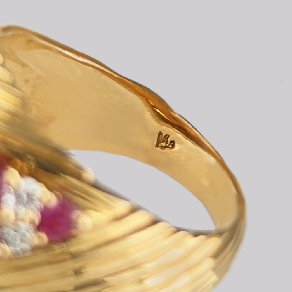 A mid-century 18ct yellow gold bombe ring styled with a ribbed textured surface and a diagonal band set with rubies and round brilliant diamonds. View IX