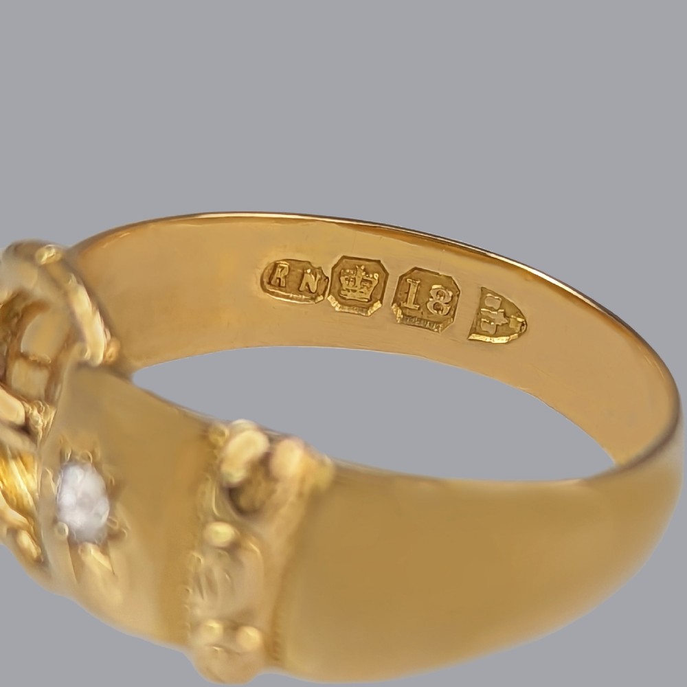 A Victorian 18ct yellow gold buckle ring featuring a central star-set diamond and British hallmark stamps visible on the inner band. View III