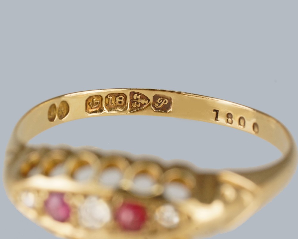 An 18ct yellow gold navette ring set with three rubies and two diamonds within a decorative carved gallery. View III