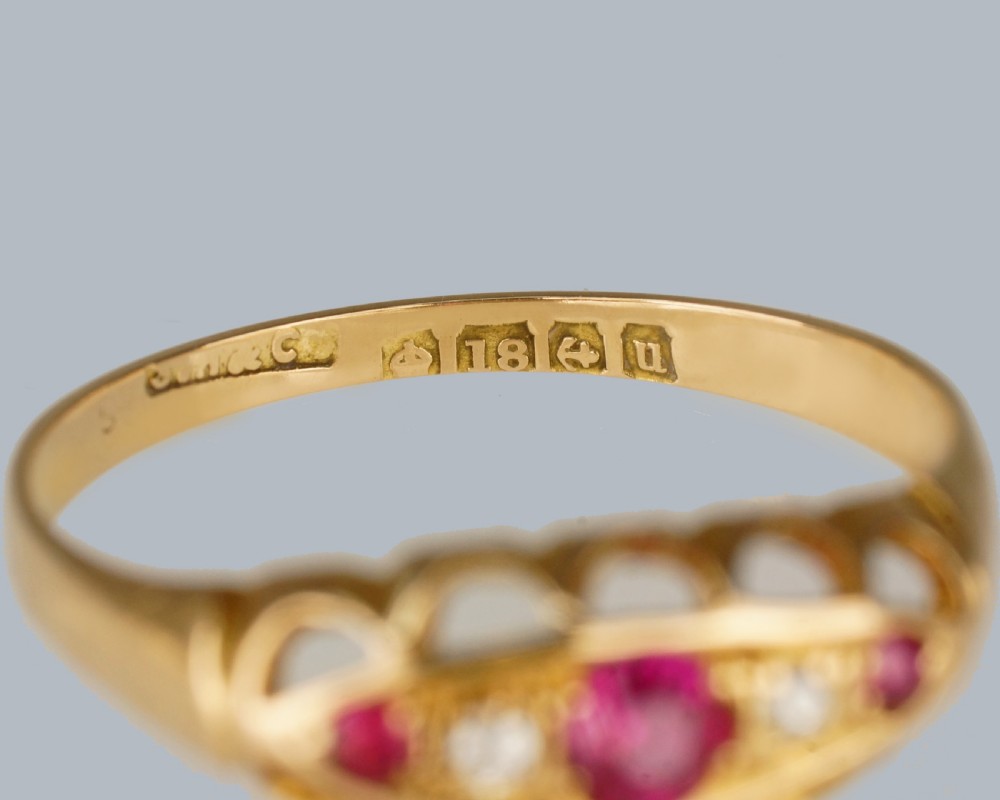An 18ct yellow gold navette ring set with three rubies and two diamonds within a decorative carved gallery. View IV