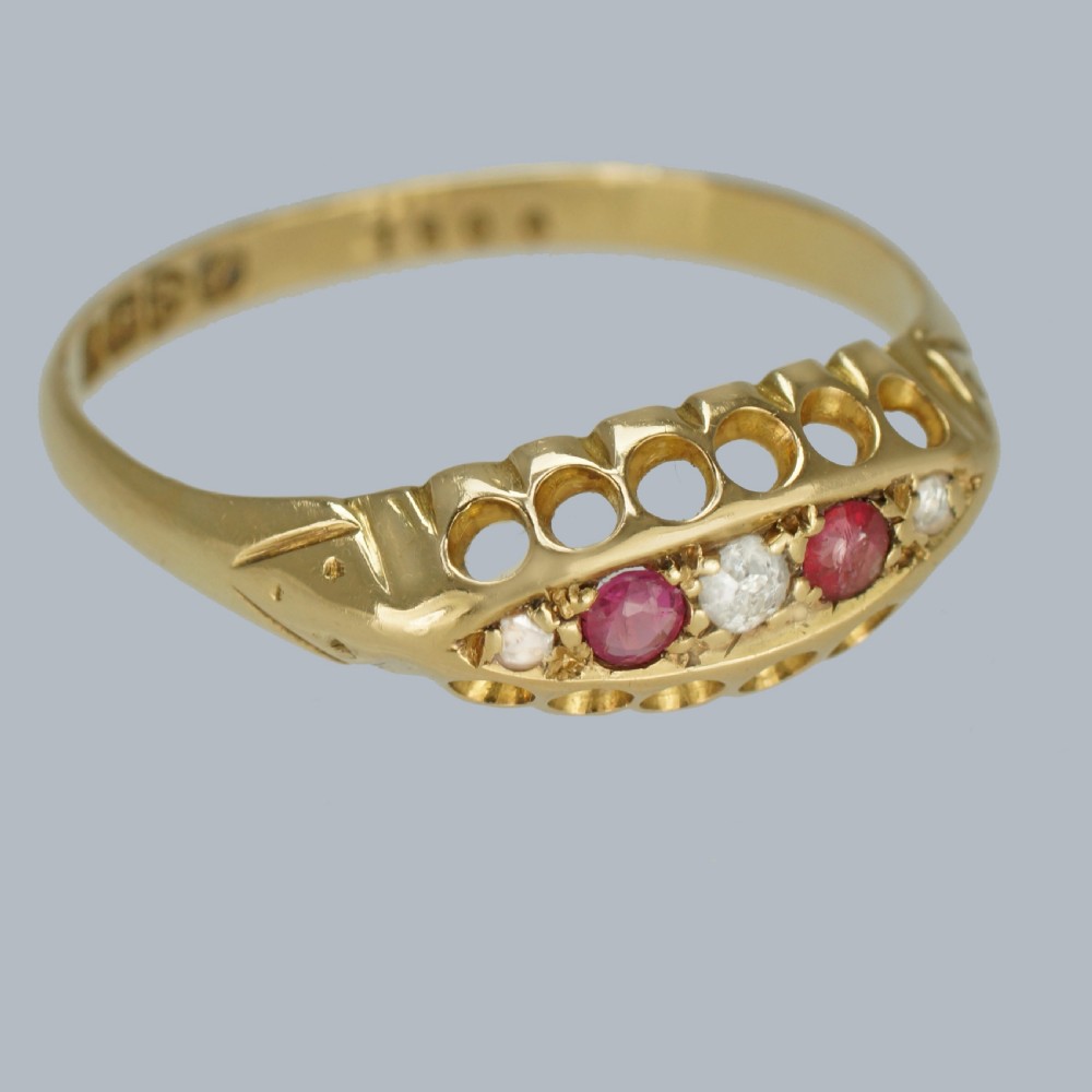 An 18ct yellow gold navette ring set with three rubies and two diamonds within a decorative carved gallery. View VI