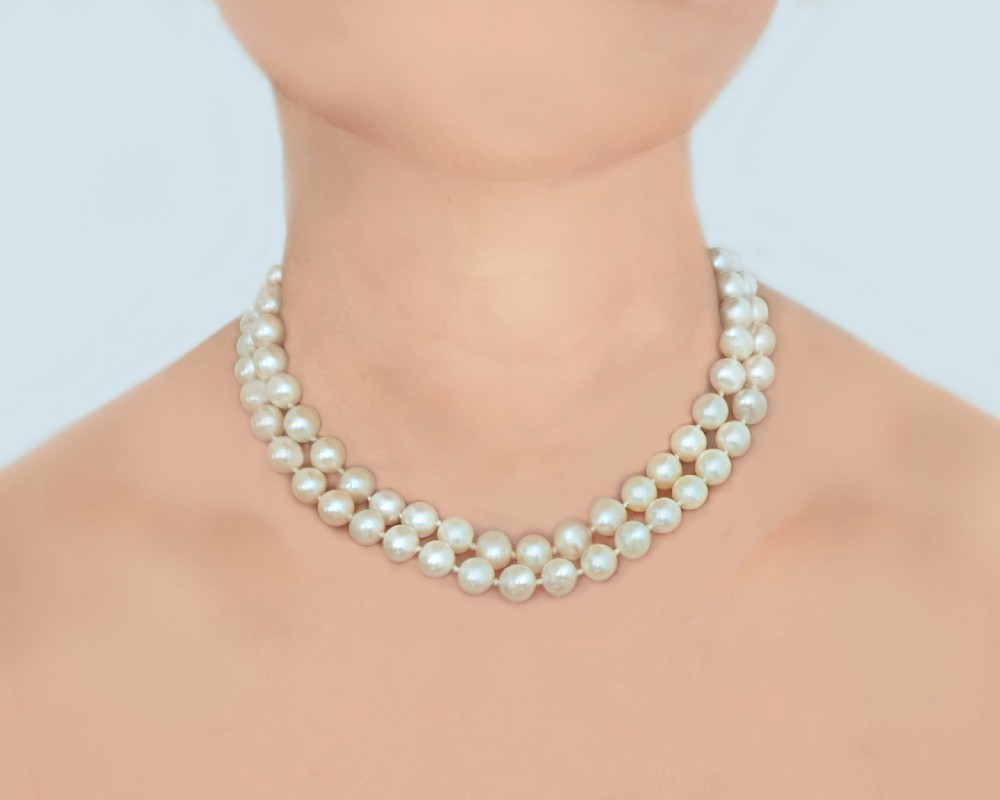 A two-strand cream cultured pearl necklace featuring an ornate circular 9ct gold clasp embellished with garnets and seed pearls. View III