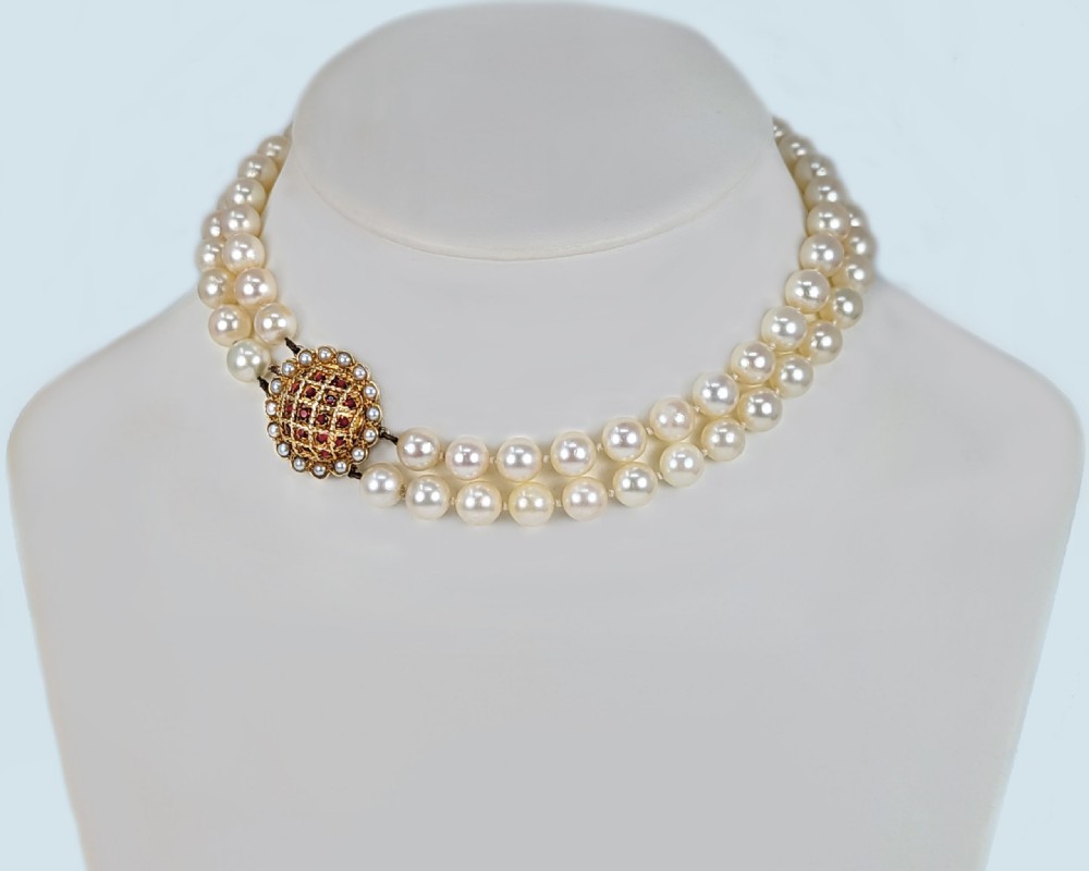 A two-strand cream cultured pearl necklace featuring an ornate circular 9ct gold clasp embellished with garnets and seed pearls. View VII