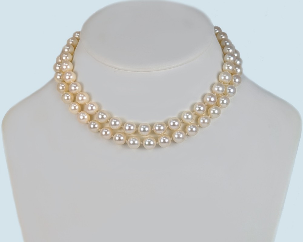 A two-strand cream cultured pearl necklace featuring an ornate circular 9ct gold clasp embellished with garnets and seed pearls. View VIII