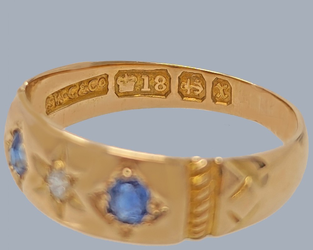 An 18ct yellow gold Victorian band featuring two oval blue sapphires flanking a central star-set diamond. View V