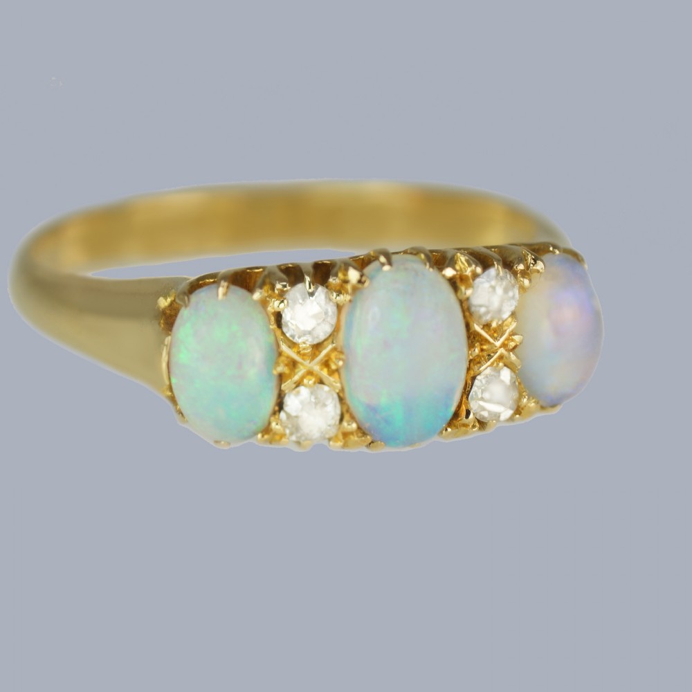 An antique 18ct yellow gold ring featuring three oval cabochon opals set horizontally with four small round diamonds placed between them. View II