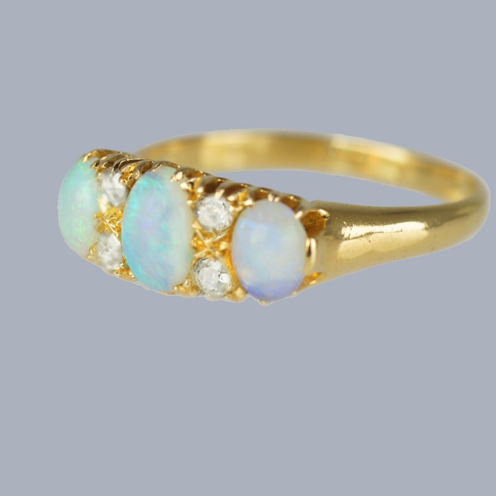 An antique 18ct yellow gold ring featuring three oval cabochon opals set horizontally with four small round diamonds placed between them. View III