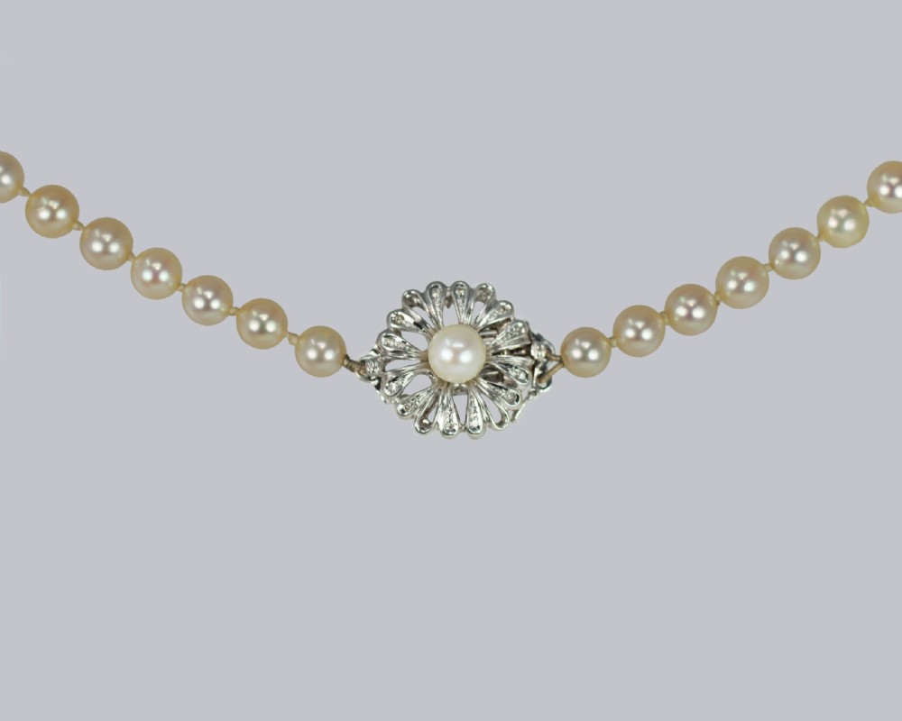 A single strand of cream-coloured pearls hand-knotted on silk thread resting neatly around a neck. View III