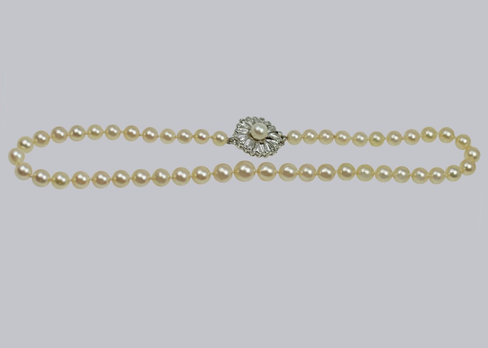A single strand of cream-coloured pearls hand-knotted on silk thread resting neatly around a neck. View VI