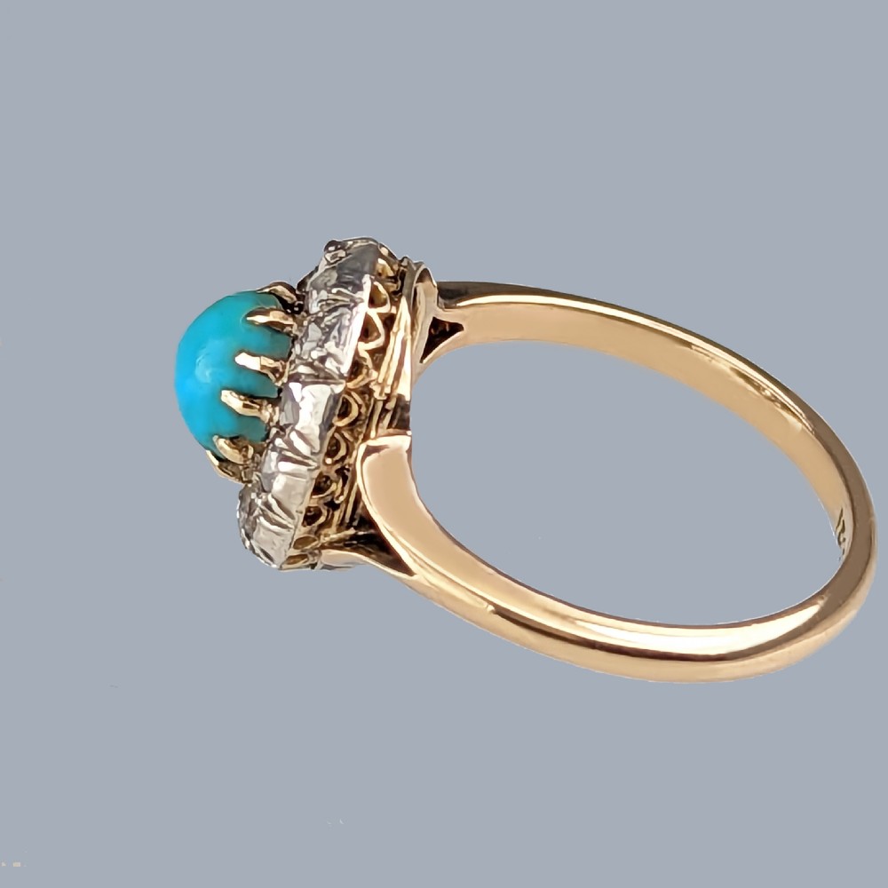 A Victorian 15ct yellow gold ring set with a bright blue oval turquoise cabochon within a halo of rose-cut diamonds. View VI