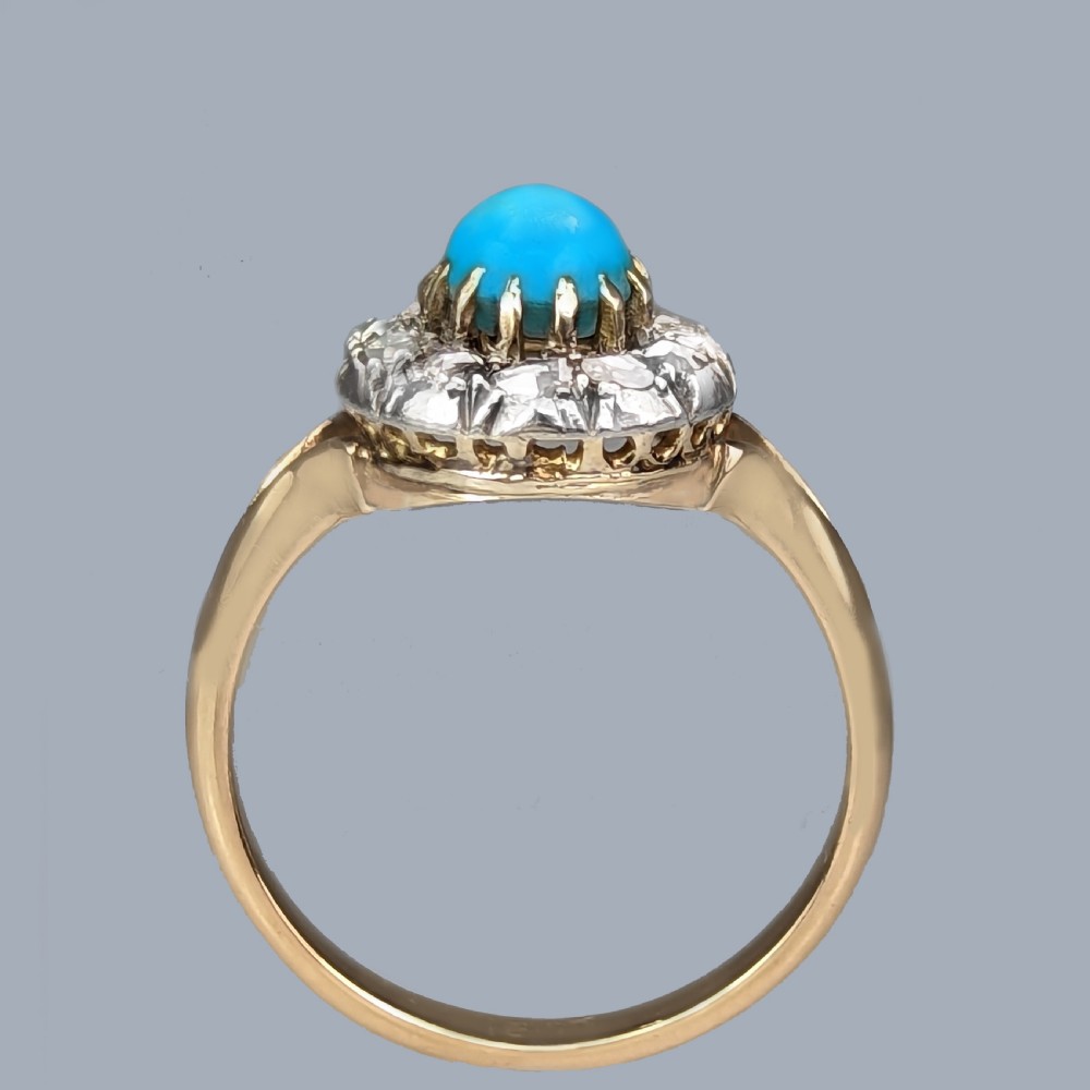 A Victorian 15ct yellow gold ring set with a bright blue oval turquoise cabochon within a halo of rose-cut diamonds. View VII