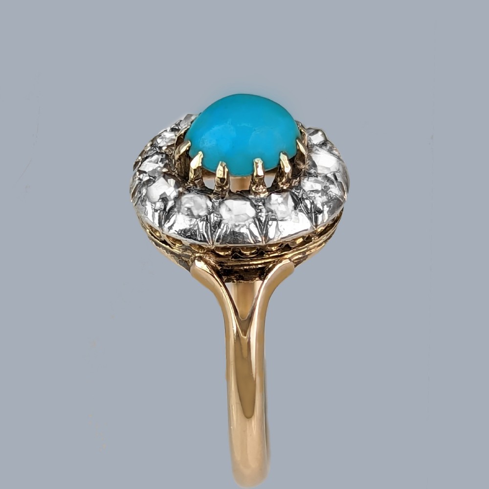 A Victorian 15ct yellow gold ring set with a bright blue oval turquoise cabochon within a halo of rose-cut diamonds. View VIII