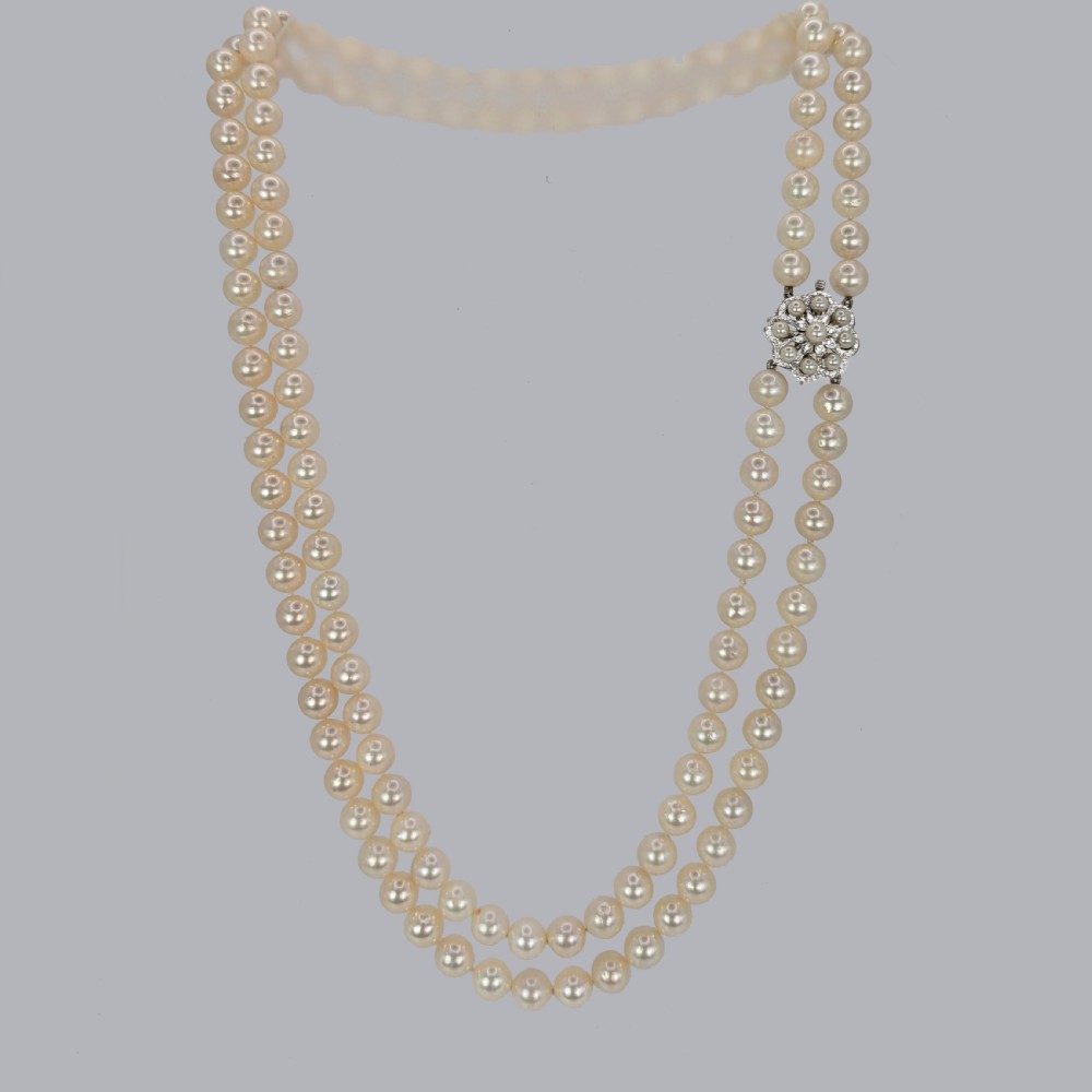 A double strand cream pearl necklace featuring an ornate white gold floral clasp set with small diamonds. View III