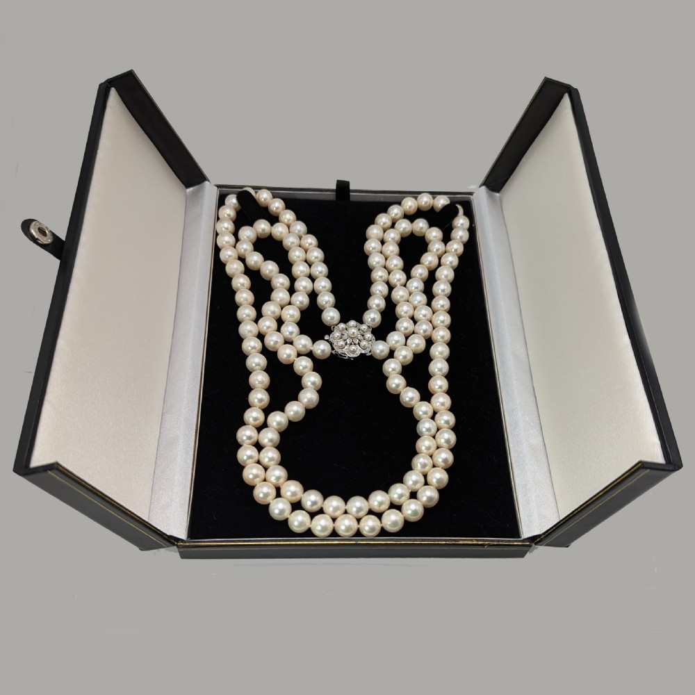 A double strand cream pearl necklace featuring an ornate white gold floral clasp set with small diamonds. View V