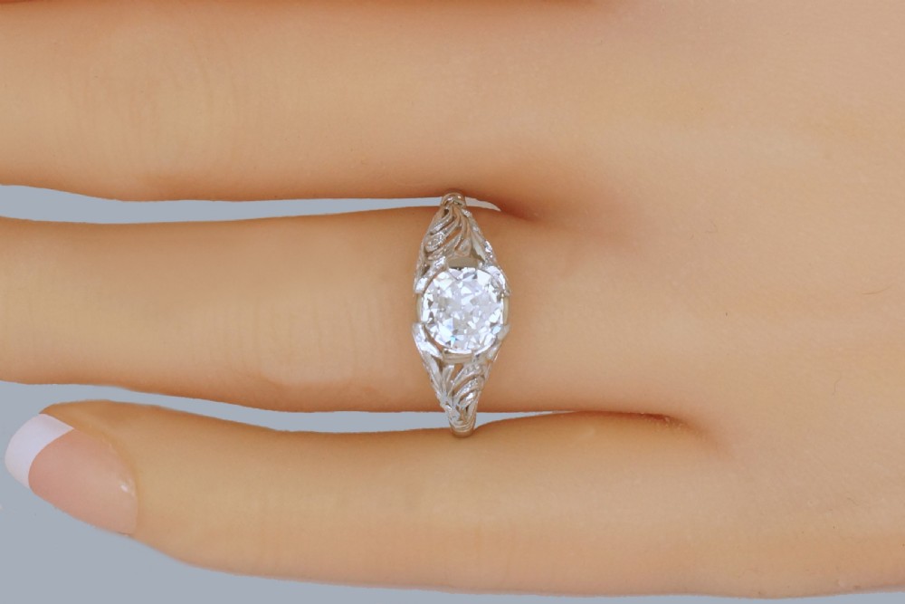 A top-down view of an Edwardian platinum solitaire ring featuring a central old cut diamond set in carved pierced shoulders. View III